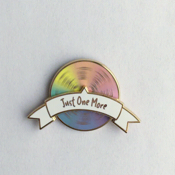 Video Gif of unique spinning enamel pin for knitters. 'Just One More Row' pin with activity options on spinning pastel rainbow wheel.