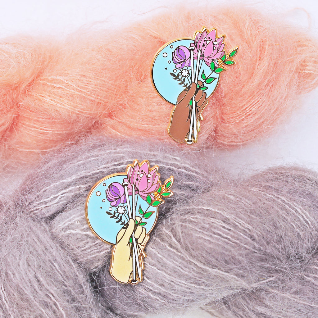Floral enamel pin for knitters. Knitting needles being held with a bouquet of flowers, available in multiple skin tones.