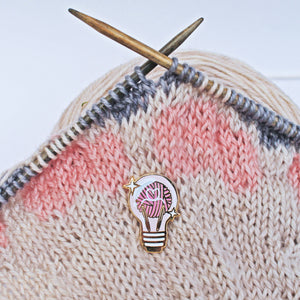 Whimsical and unique enamel pin for knitters. Yarn ball and knitting needles displayed inside a lightbulb. 