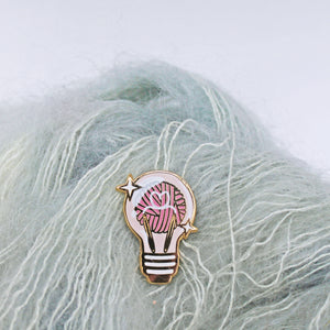 Whimsical and unique enamel pin for knitters. Yarn ball and knitting needles displayed inside a lightbulb.